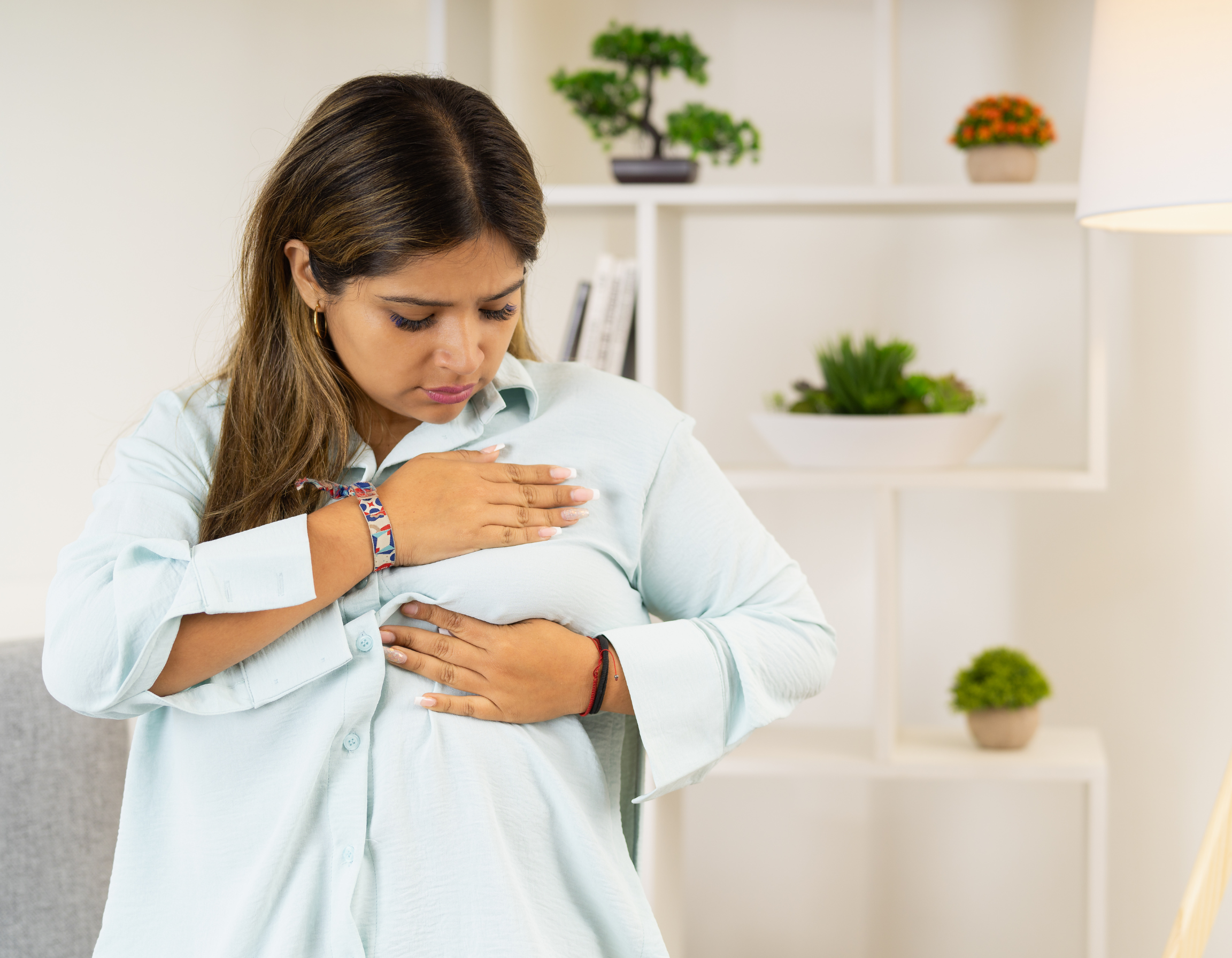 Woman performing a breast self-examination at home, checking for lumps or changes in breast tissue. Image represents early signs of breast cancer, breast health awareness, self-examination, and the importance of early detection and timely diagnosis for women’s health.
